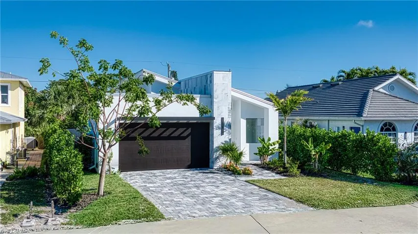View of front of home with a front lawn, decorative driveway, and stucco siding