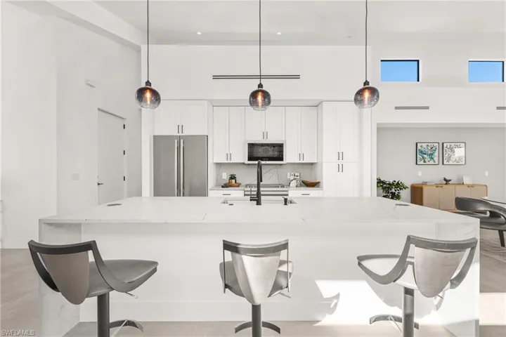 Kitchen with freestanding refrigerator, a sink, backsplash, and a high ceiling
