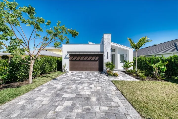 View of front of property featuring an attached garage, a front lawn, decorative driveway, and stucco siding