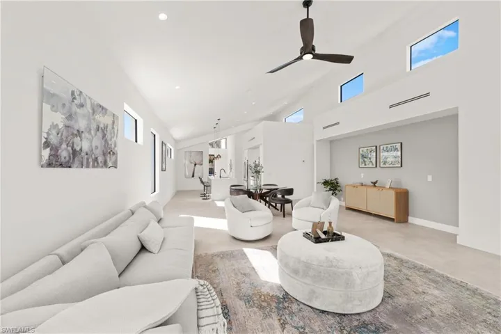 Living room featuring recessed lighting, a high ceiling, finished concrete floors, ceiling fan, and baseboards
