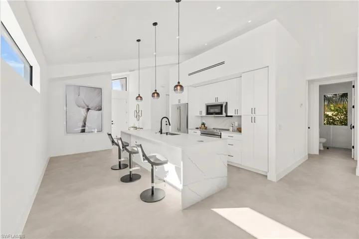 Kitchen featuring a breakfast bar area, appliances with stainless steel finishes, a kitchen island with sink, white cabinetry, and a sink