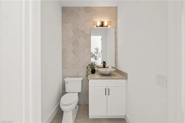 Bathroom featuring vanity, toilet, and baseboards