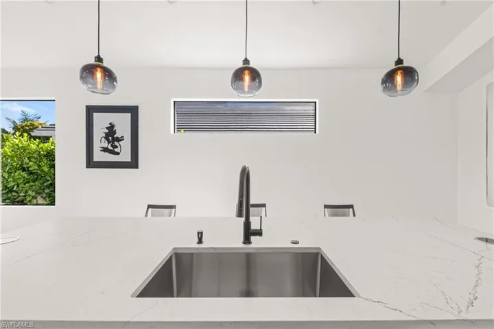 Details with pendant lighting, a sink, and light stone countertops