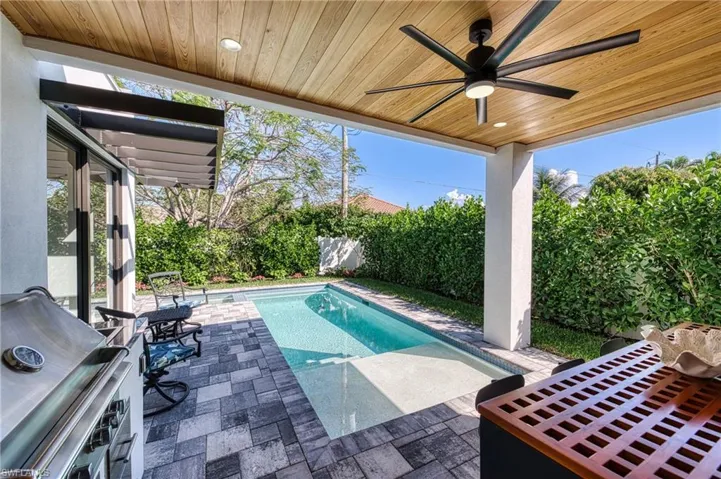 View of swimming pool with ceiling fan, a fenced backyard, a grill, a fenced in pool, and a patio area