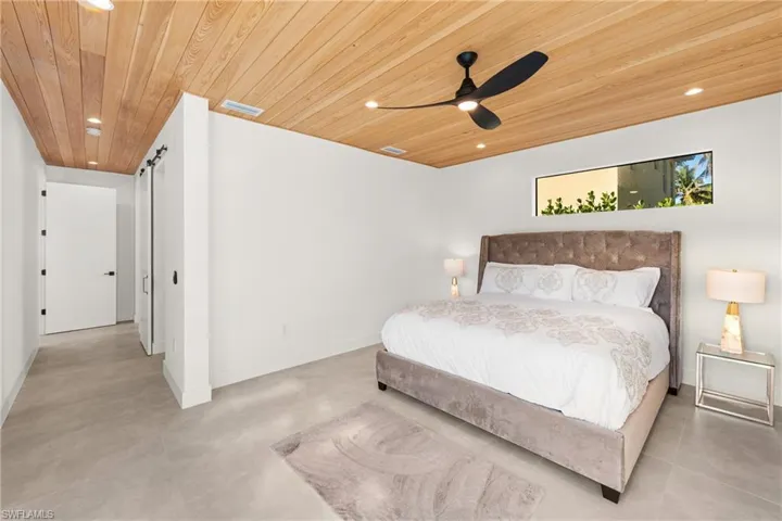 Bedroom with recessed lighting, wooden ceiling, visible vents, and a barn door