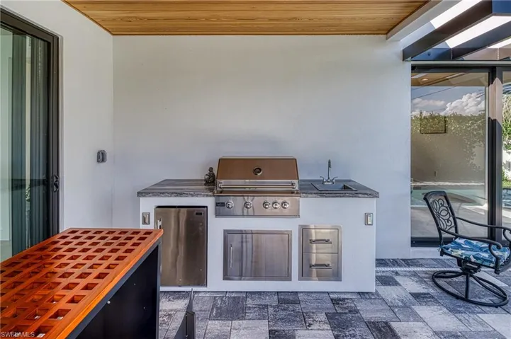 View of patio featuring area for grilling, a grill, and a sink