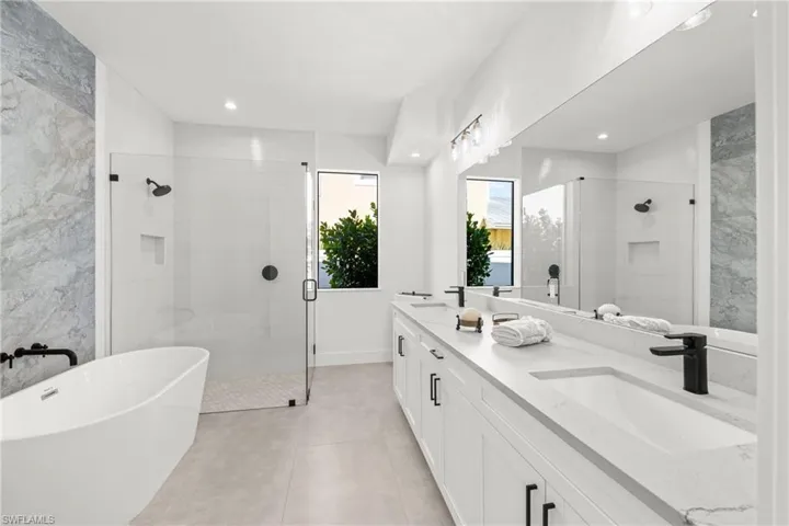 Full bathroom featuring a sink, a shower stall, a freestanding bath, and double vanity