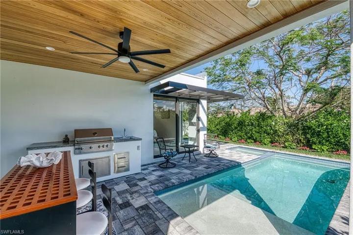 View of swimming pool featuring area for grilling, a ceiling fan, grilling area, a fenced in pool, and a patio area