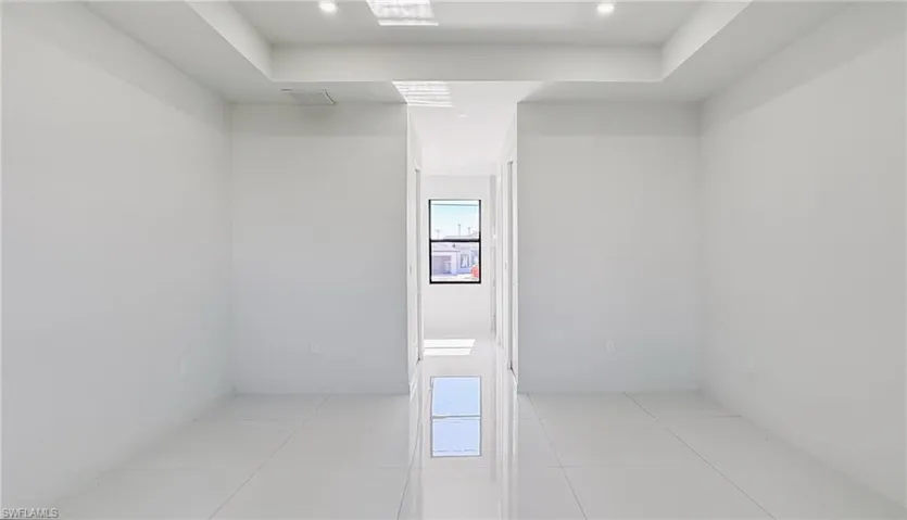 Tiled spare room featuring a tray ceiling