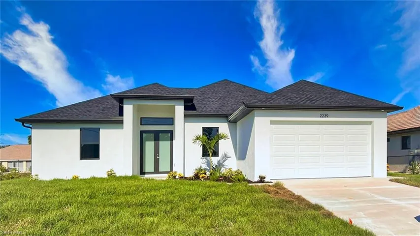 View of front of property featuring a garage and a front lawn