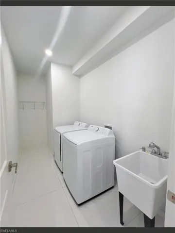Laundry area featuring sink, light tile patterned flooring, and washer and dryer
