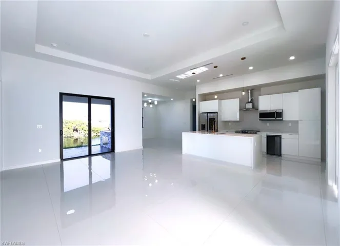 Kitchen featuring appliances with stainless steel finishes, a tray ceiling, and light tile patterned floors