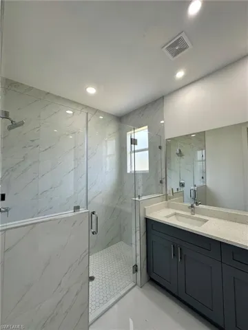 Bathroom featuring tile floors, an enclosed shower, and vanity