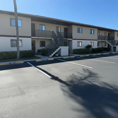 View of apartment complex with stairs and uncovered parking