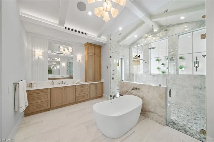 Bathroom featuring vanity, shower with separate bathtub, vaulted ceiling with beams, and tile walls
