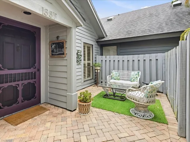 Private courtyard entry featuring herringbone brick pavers and a decorative purple screen door