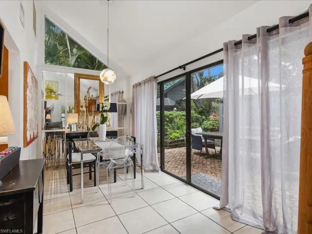Dining area featuring vaulted ceilings, a prominent triangular transom window, and tile flooring