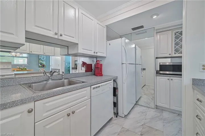 Well-equipped kitchen with abundant white cabinetry, ample counter space, tile flooring custom cabinetry and appliances included—everything you need to move right in and start enjoying your Florida getaway.