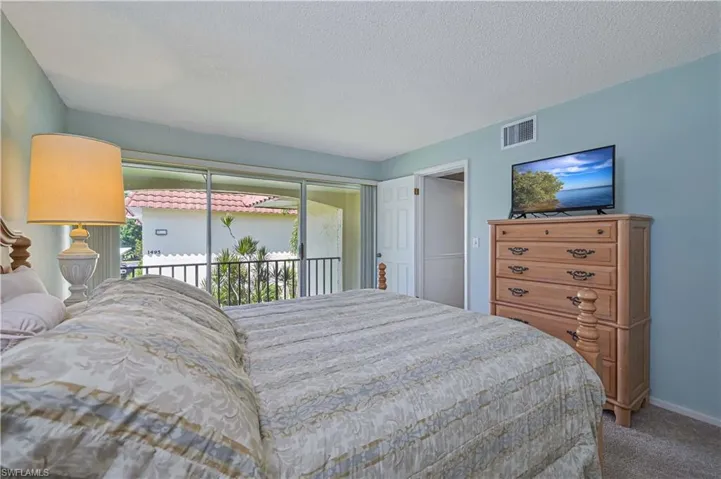 Sliding glass doors fill the primary bedroom with natural light and open directly to its own private covered balcony.