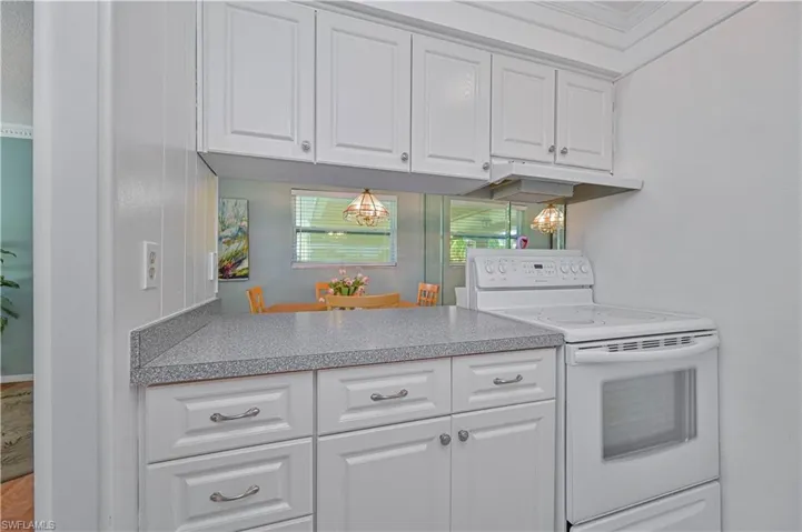 Bright kitchen with crisp white cabinetry, generous counter space and a convenient pass-through to the dining area—perfect for casual meals and entertaining.