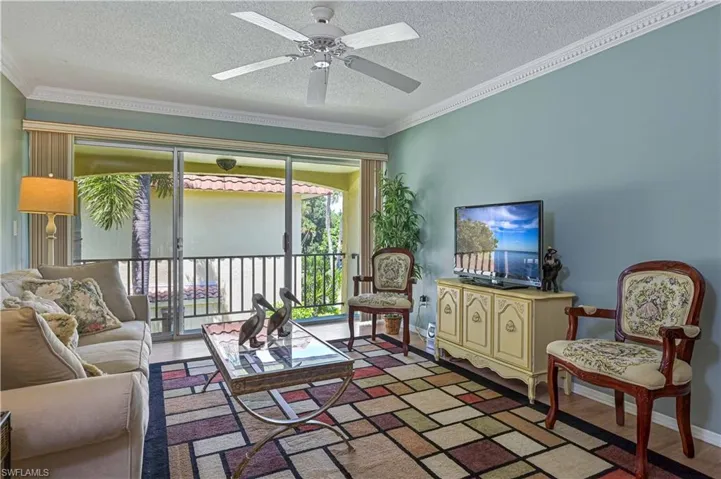 Bright and spacious living area with sliding glass doors opening to the private balcony, bringing in plenty of natural light and a relaxed Florida feel.