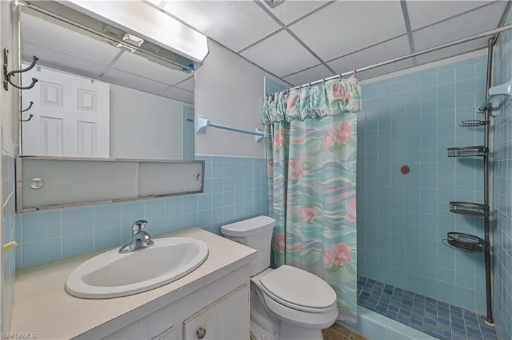 Full bathroom with a tiled walk-in shower, large mirrored vanity and convenient built-in shower storage.
