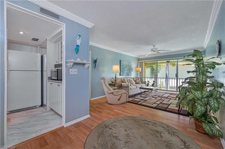 A great view of the condo’s open, flowing floor plan connecting the kitchen, dining and living areas, with laminate wood flooring, crown molding and abundant natural light.