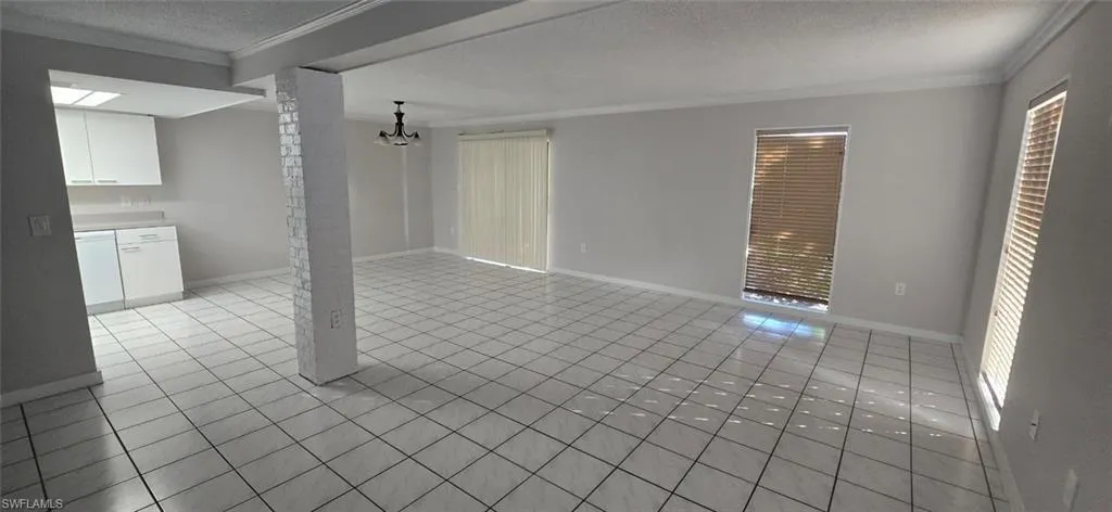 Unfurnished living room featuring a textured ceiling, crown molding, and light tile patterned flooring