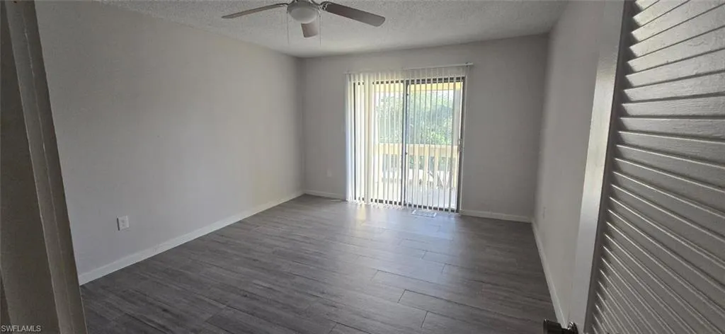 Unfurnished room with a textured ceiling, dark wood-type flooring, and a ceiling fan