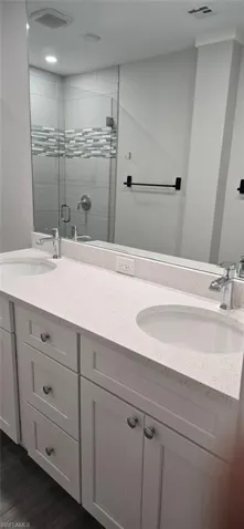 Full bath featuring double vanity and a stall shower