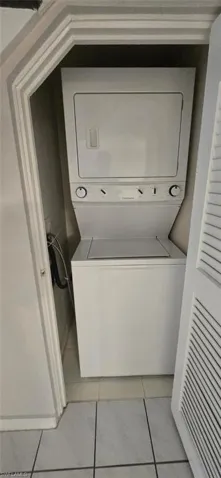 Laundry area featuring stacked washer / dryer and light tile patterned floors