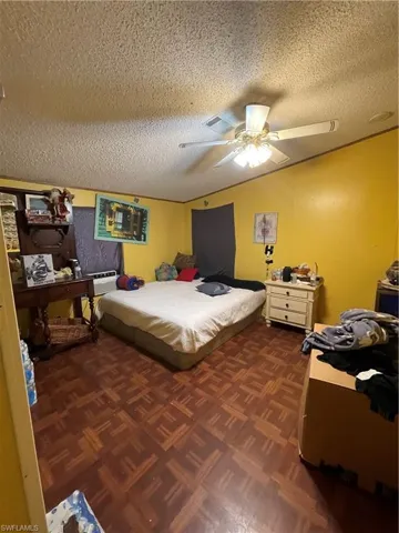 Bedroom featuring dark parquet flooring, ceiling fan, and a textured ceiling