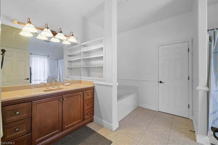 Kitchen with ornamental molding, light countertops, backsplash, decorative light fixtures, and light tile patterned floors