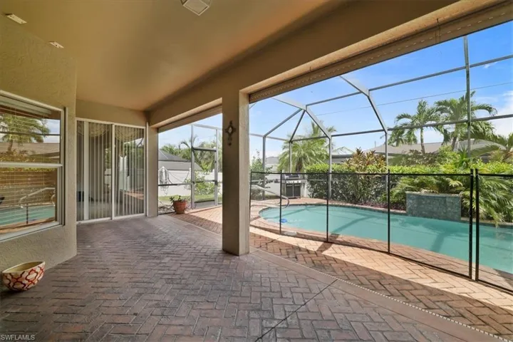 Outdoor pool with a sunroom, glass enclosure, and a patio area