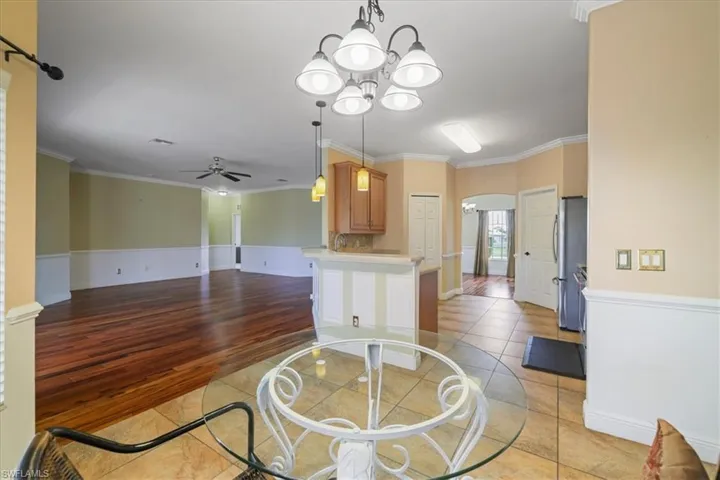 Unfurnished dining area with arched walkways, wood-type flooring, crown molding, and a chandelier