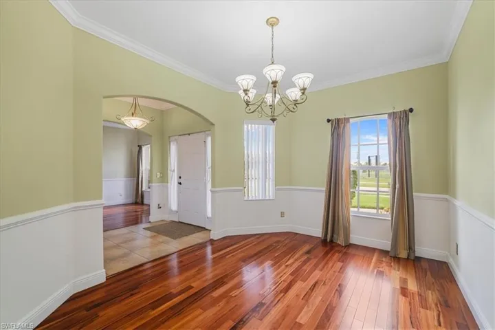 Kitchen with appliances with stainless steel finishes, a chandelier, light countertops, crown molding, and hanging light fixtures