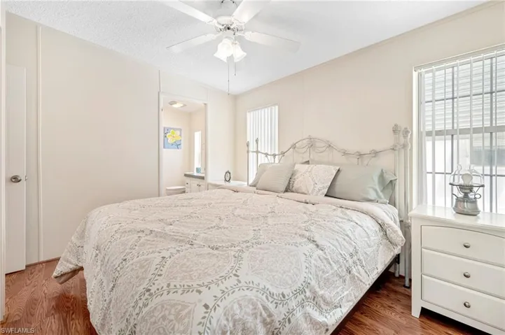 Bedroom featuring a textured ceiling, ceiling fan, connected bathroom, and wood finished floors