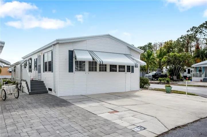 View of property exterior with concrete driveway and a carport