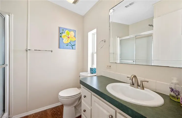 Full bath featuring visible vents, toilet, a shower stall, vanity, and wood finished floors