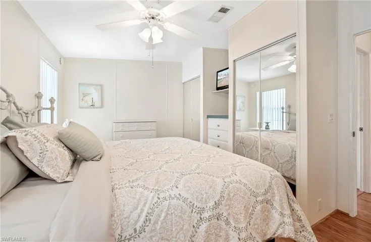 Bedroom featuring multiple closets, a ceiling fan, visible vents, and wood finished floors