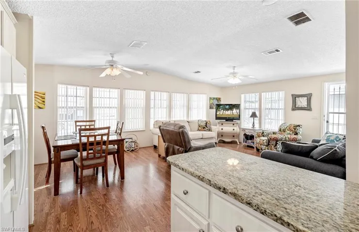 Kitchen featuring white fridge with ice dispenser, visible vents, and wood finished floors