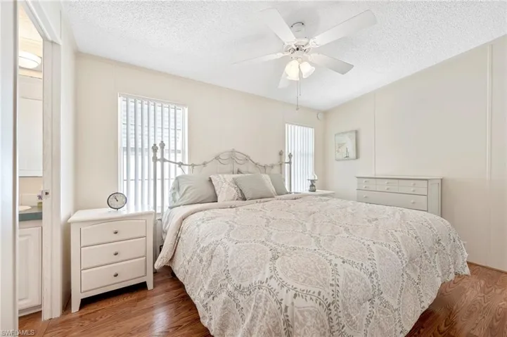 Bedroom featuring light wood-style floors, multiple windows, a textured ceiling, and a ceiling fan