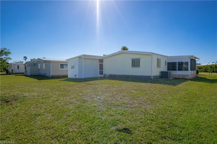 Back of house featuring central AC unit and a lawn