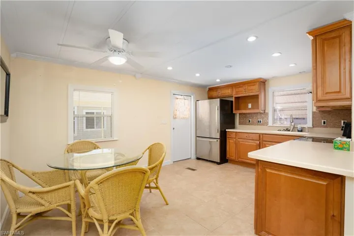 Kitchen with sink, crown molding, stainless steel fridge, ceiling fan, and decorative backsplash