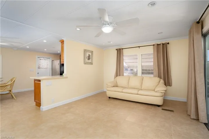 Tiled living room with crown molding and ceiling fan