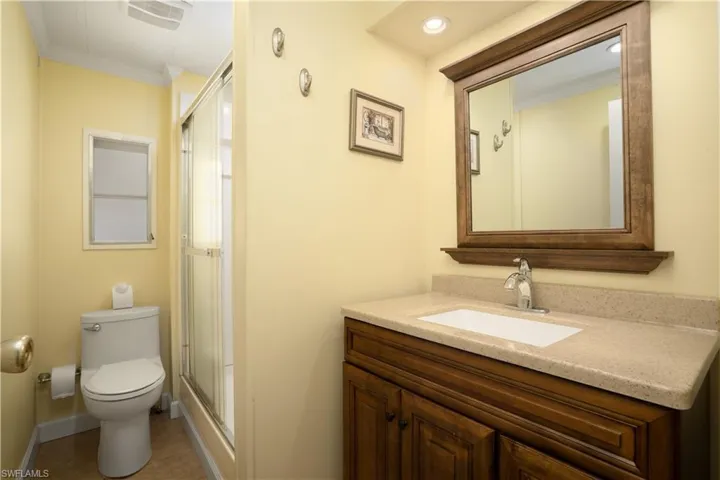 Bathroom with vanity, ornamental molding, a shower with shower door, tile patterned floors, and toilet