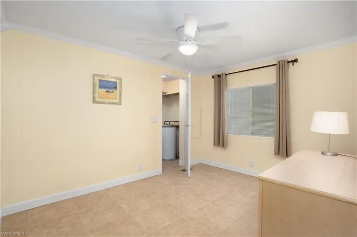 Unfurnished bedroom featuring crown molding, a spacious closet, light tile patterned floors, and ceiling fan