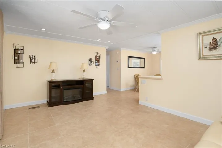 Tiled living room with crown molding and ceiling fan