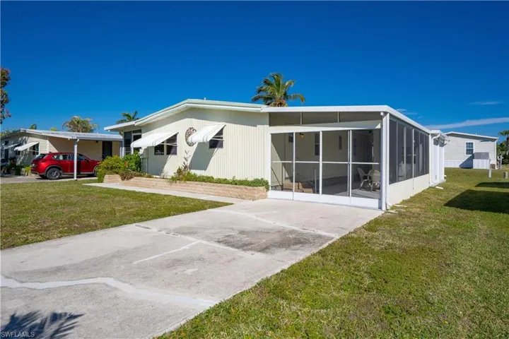 Rear view of property featuring a carport, a yard, and a sunroom