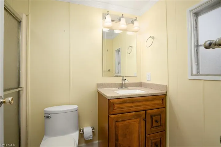 Bathroom with vanity, ornamental molding, an enclosed shower, and toilet
